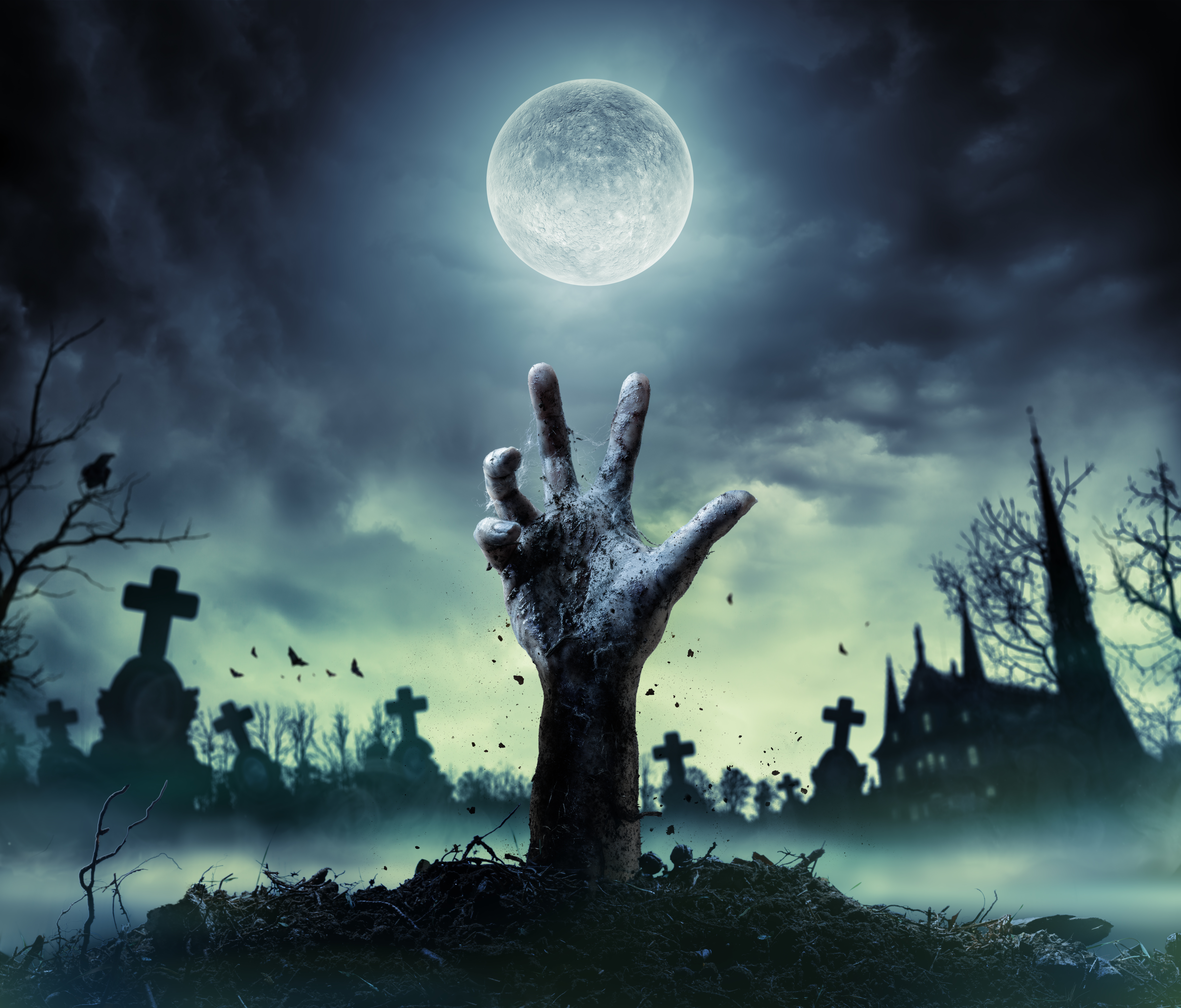 Eine Hand ragt bei Vollmond aus einem inszenierten düsteren Friedhof – Halloween-Symbolmotiv.