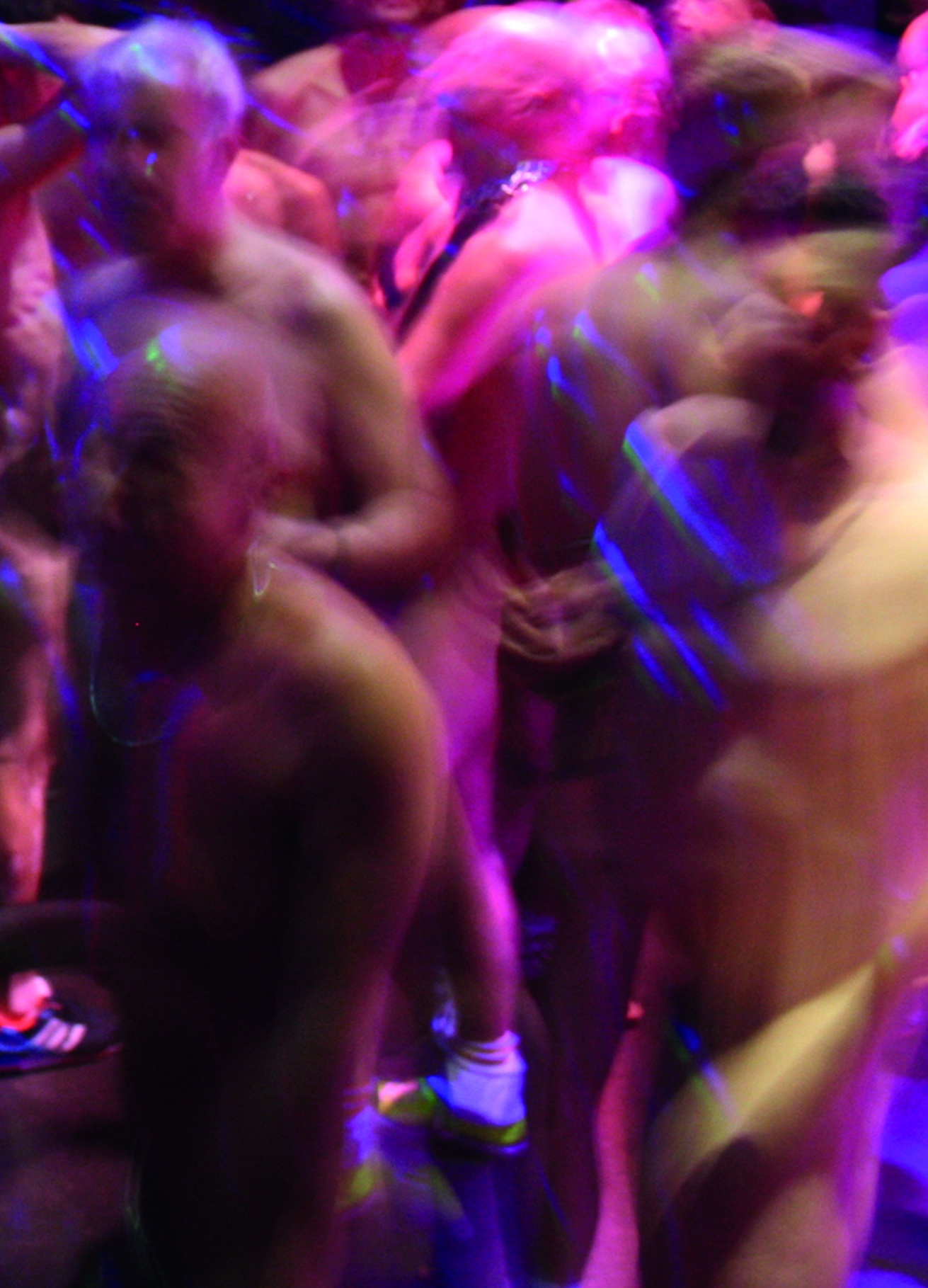 Gäste tanzen bei der NacktSchlagerSause im farbigen Partylicht.