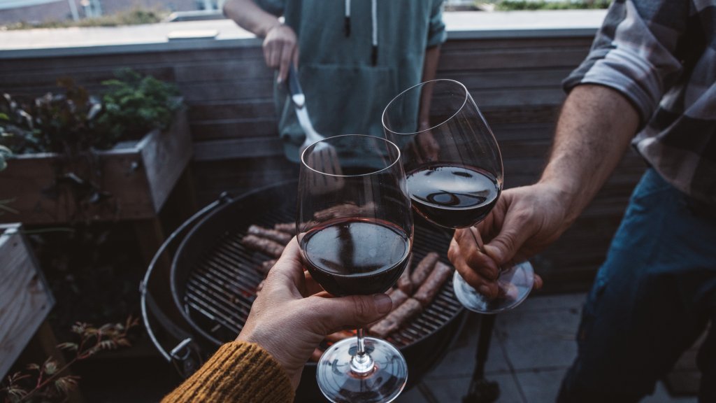 Anstoßen mit Rotwein neben dem Grill