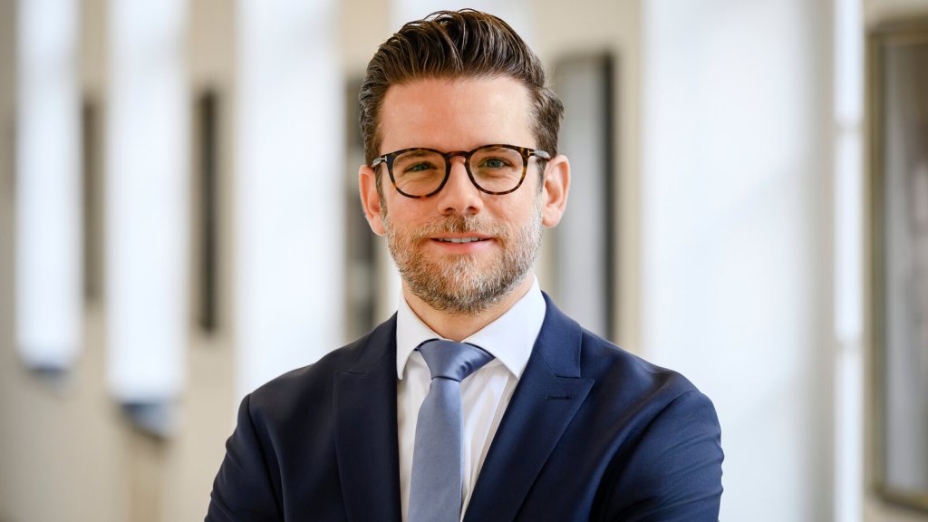 Felix Heinrichs im Anzug vor einem hellen Säulengang