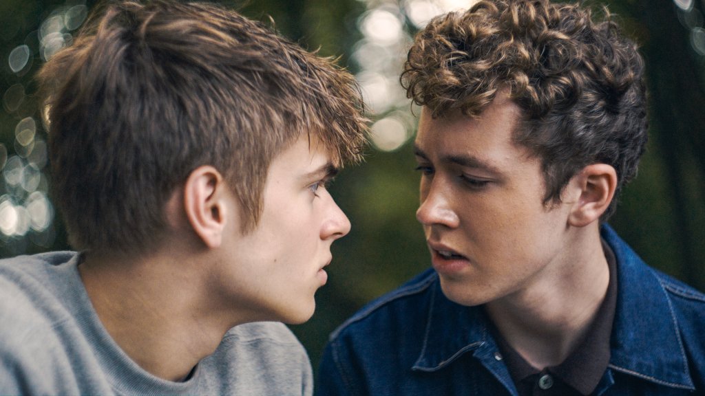 Szenenbild aus dem Film „Free at Heart“: Zwei junge Männer sitzen sich im Freien dicht gegenüber und schauen einander an.
