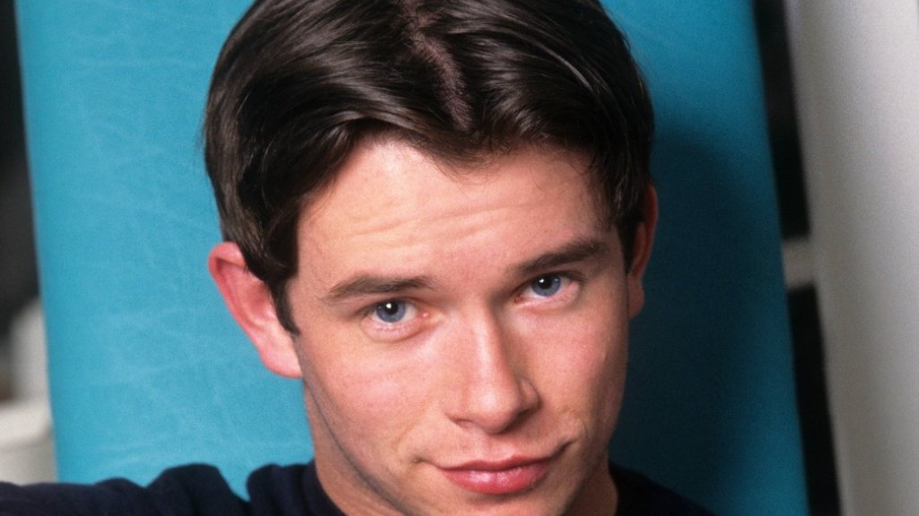 Stephen Gately in einem dunklen Calvin-Klein-T-Shirt vor türkisfarbenem Hintergrund