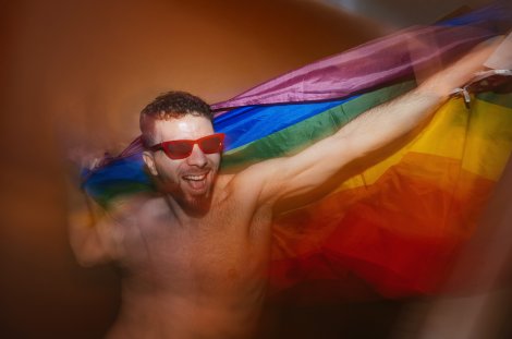 Feiernder Mann mit Regenbogenflagge (Symbolbild)