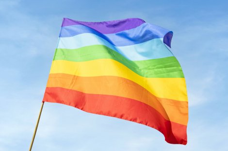 Regenbogenflagge vor blauem Himmel