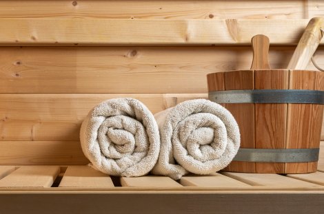 Weiße Handtücher und ein Aufgusseimer in einer Sauna – Symbolbild.