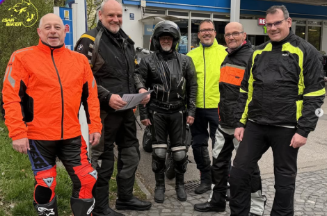 Sechs Mitglieder der IsarBiker stehen in Motorradkleidung gemeinsam vor einem Gebäude und lächeln in die Kamera.