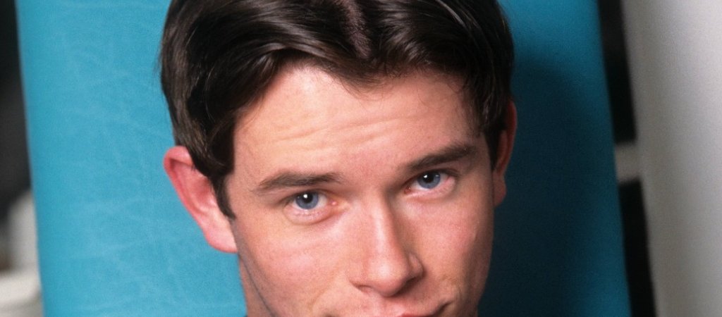Stephen Gately in einem dunklen Calvin-Klein-T-Shirt vor türkisfarbenem Hintergrund