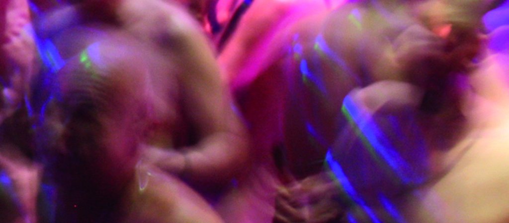 Gäste tanzen bei der NacktSchlagerSause im farbigen Partylicht.