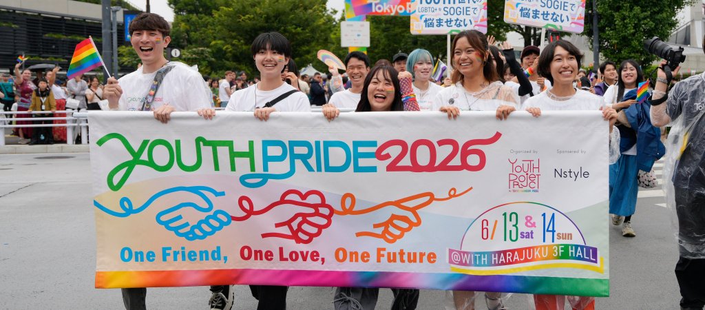 Teilnehmende der Tokyo Pride 2026 tragen ein buntes Youth-Pride-Banner und Regenbogenfahnen durch Tokio.