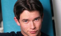 Stephen Gately in einem dunklen Calvin-Klein-T-Shirt vor türkisfarbenem Hintergrund