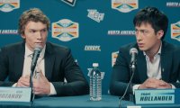 Connor Storrie und Hudson Williams als Ilya und Shane bei einer Pressekonferenz in Heated Rivalry (Szenenbild).