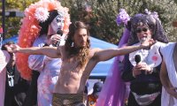 Filmstill aus Hunky Jesus: Jesus-Darsteller mit ausgebreiteten Armen zwischen den Sisters of Perpetual Indulgence