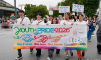 Teilnehmende der Tokyo Pride 2026 tragen ein buntes Youth-Pride-Banner und Regenbogenfahnen durch Tokio.