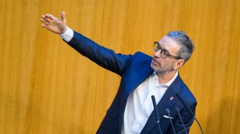 Herbert Kickl an einem Rednerpult mit ausgestrecktem Arm (Archivbild)