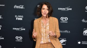 Ulrike Folkerts im karierten Hosenanzug bei einem Fototermin auf dem roten Teppich