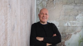 Pastor Malte Stets lächelt vor einer hellen Wand in die Kamera.