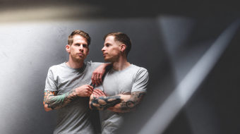 Zwei Männer in grauen T-Shirts stehen nebeneinander – Symbolbild