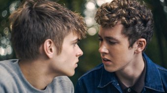 Szenenbild aus dem Film „Free at Heart“: Zwei junge Männer sitzen sich im Freien dicht gegenüber und schauen einander an.