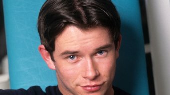 Stephen Gately in einem dunklen Calvin-Klein-T-Shirt vor türkisfarbenem Hintergrund
