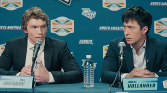 Connor Storrie und Hudson Williams als Ilya und Shane bei einer Pressekonferenz in Heated Rivalry (Szenenbild).