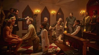 Ensembleszene aus Imagine: Menschen versammeln sich im Kirchenraum des Bühnendorfs.