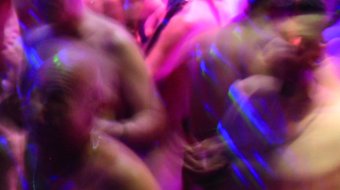 Gäste tanzen bei der NacktSchlagerSause im farbigen Partylicht.