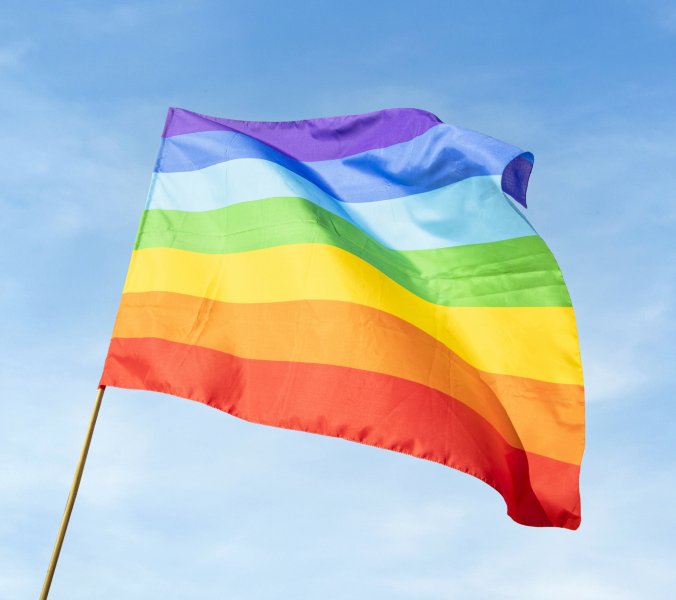 Regenbogenflagge vor blauem Himmel